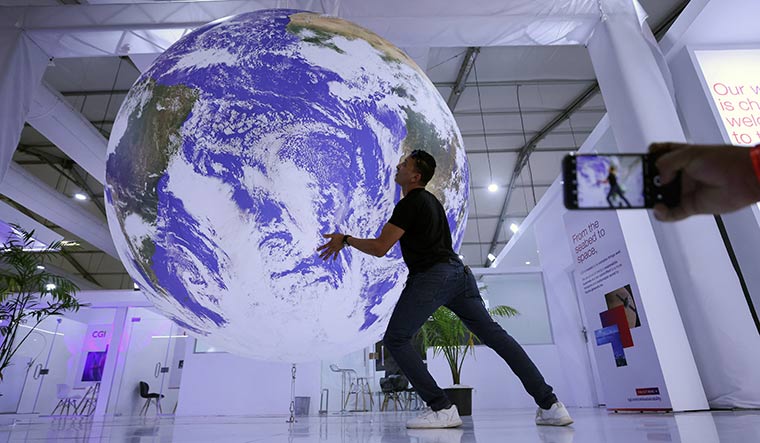 Save the planet: A person poses for a picture near a replica of the earth during the COP27 summit in Egypt | Reuters
