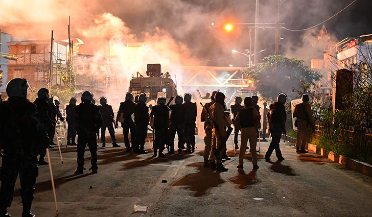 Acting tough: Security personnel firing tear gas shells to disperse a violent crowd in Imphal.