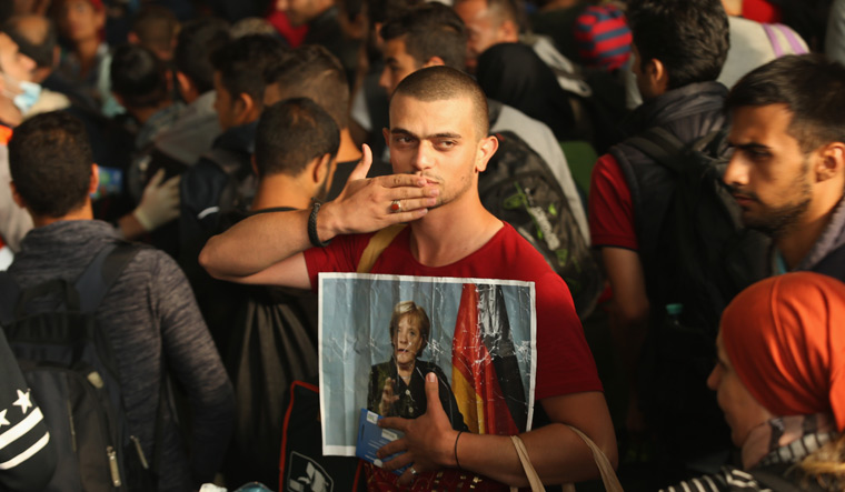 Mother's mercy: A migrant from Syria with a photo of Merkel, in Munich, in 2015 | Getty Images