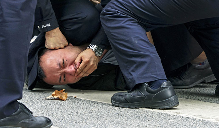 Enforced silence: Policemen pin down and arrest a protester in Shanghai | AP
