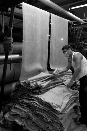 A worker checks the quality of a product at a jute mill.