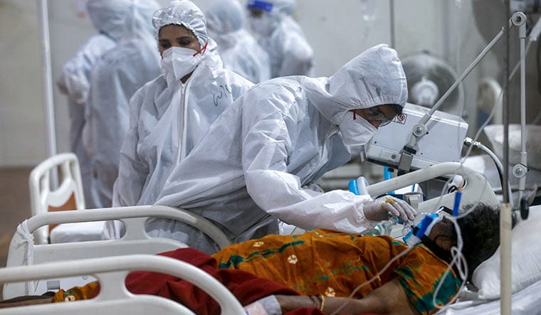 Need for intervention: A health worker adjusts the oxygen mask of a patient in Mumbai. The Supreme Court has appointed a task force to coordinate oxygen allocation and distribution across the country | AP