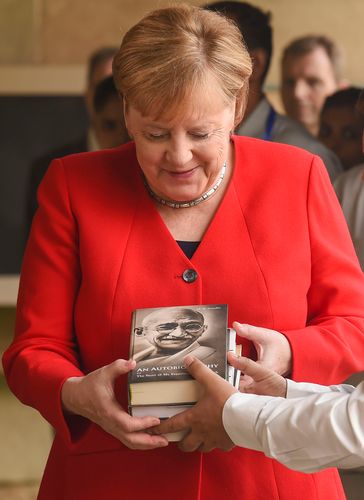 A visit to remember: Merkel being presented books after she paid homage at the samadhi of Mahatma Gandhi at Rajghat in New Delhi in 2019 | PTI