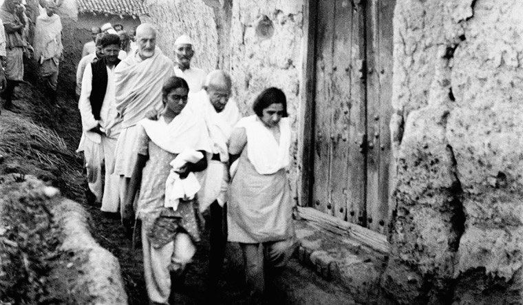 In lockstep: Mahatma Gandhi, supported by Mridula Sarabhai (right) and Manu Gandhi, walking with Khan Abdul Gaffar Khan and others through a  riot-stricken village | DINODIA