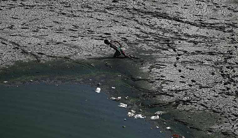 Scorched earth: A boy walks across a patch of the dry Yamuna riverbed in Delhi | AFP