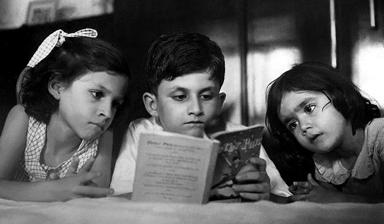 Lost in fantasy: Salman Rushdie, aged 7, reading Peter Pan with sisters Sameen (left) and Nevid | Alamy
