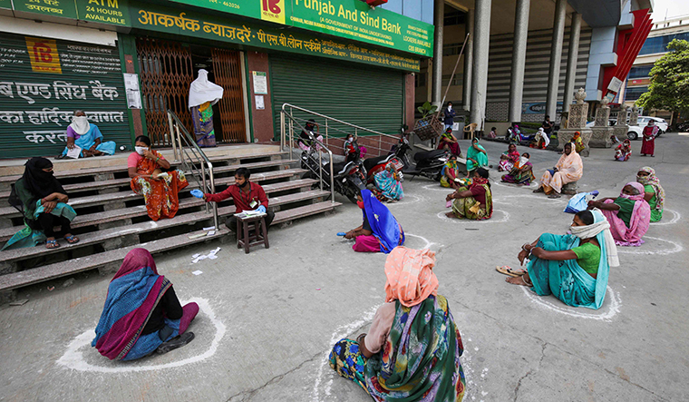 Women maintain social distancing outside a bank in Bhopal as they wait to collect their pension | AFP