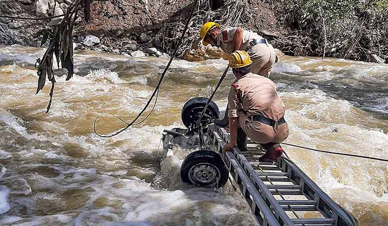 Nature’s fury: Search and rescue team officials recover mangled remains of a vehicle from a stream at Gadsa valley, in Kullu | PTI