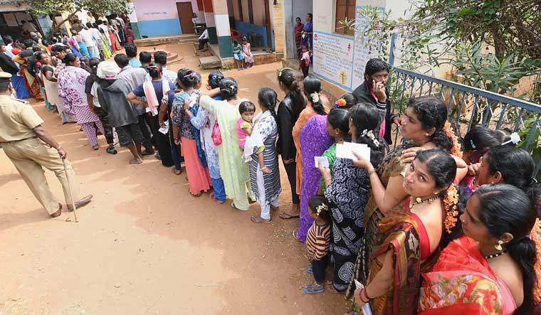 Voters stand in a queue to cast their votes during Hunsur Assembly by-elections in Karnataka, at Hunsur in Mysore | PTI