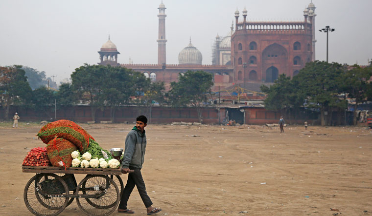 A vegetable vendor pulls his hand cart as he heads to the market in New Delhi | AP