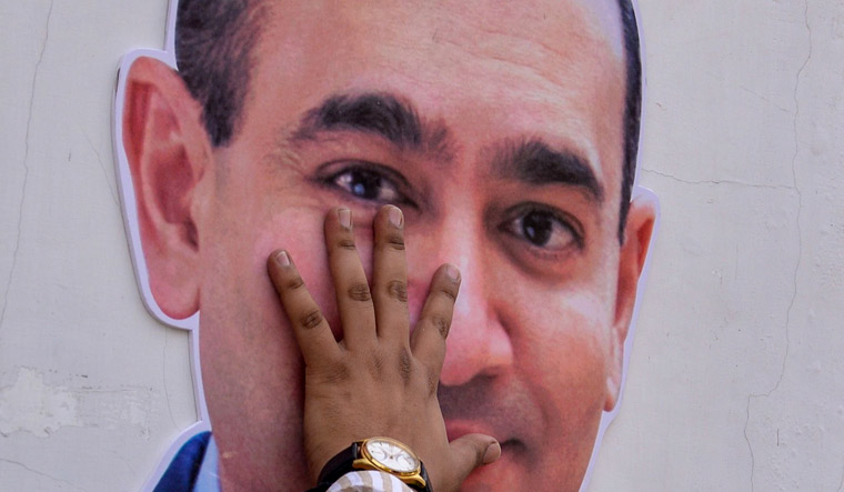 (File) A man puts his hand on the face of a cut-out of billionaire jeweller Nirav Modi during a protest in New Delhi | AFP