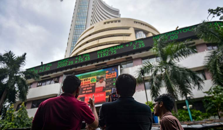 Bystanders react as they watch the stock prices displayed on a digital screen outside BSE building, in Mumbai | PTI