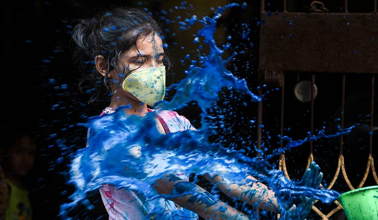 A child wearing protective masks as a precautionary measure amid the coronavirus scare is seen smeared in dry colours during Holi festival celebrations, in Chennai | PTI