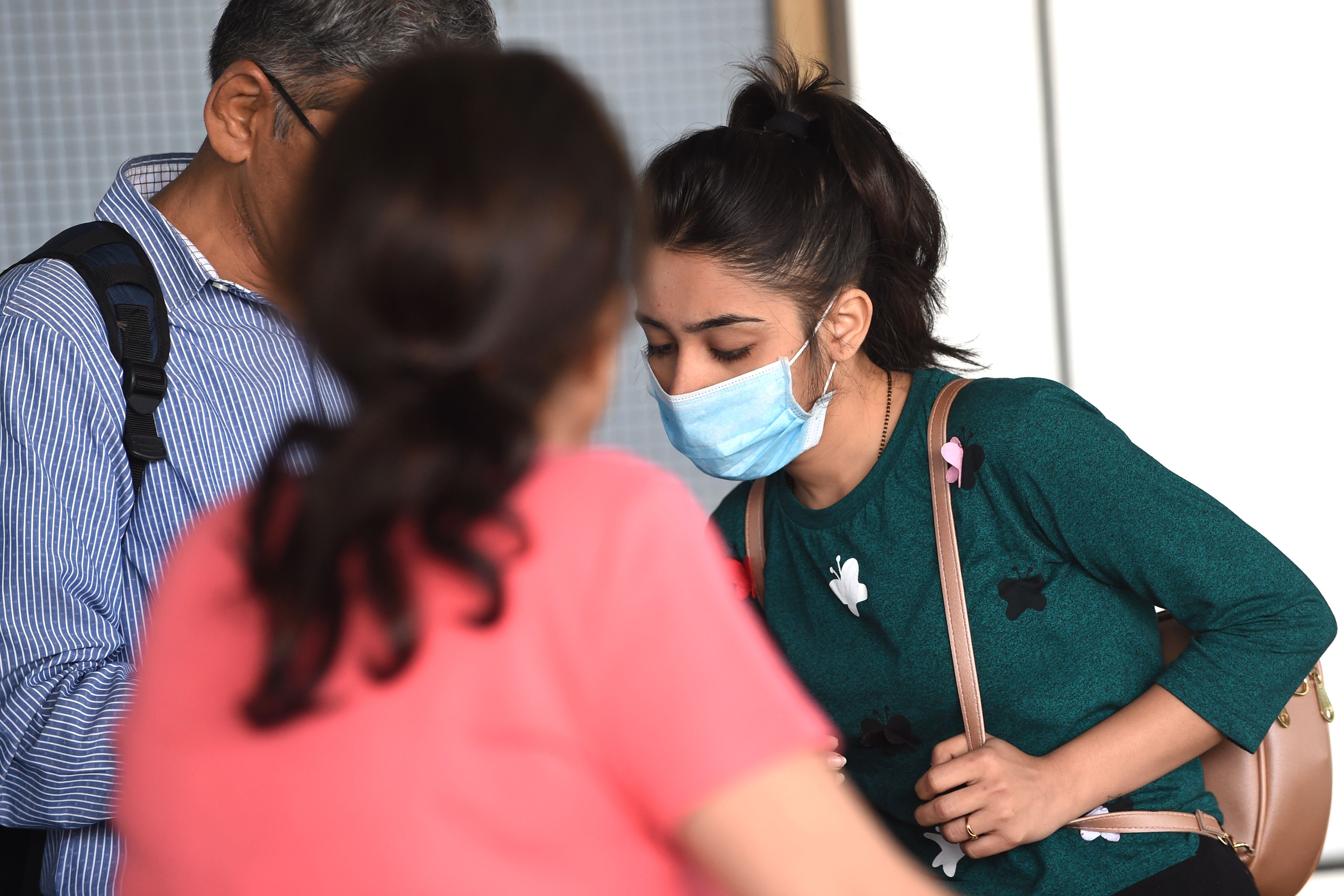A passenger wearing a facemask as a preventive measure against the spread of the COVID-19 coronavirus outbreak, interacts with her relatives upon her arrival at the Sardar Vallabhbhai Patel international airport in Ahmedabad on March 4, 2020. - India confirmed three cases in late January and early February, all of whom arrived from China and who have since recovered. But until last week no more infections were reported when an Indian man who returned from Italy via Austria to New Delhi tested positive. (Photo by SAM PANTHAKY / AFP)