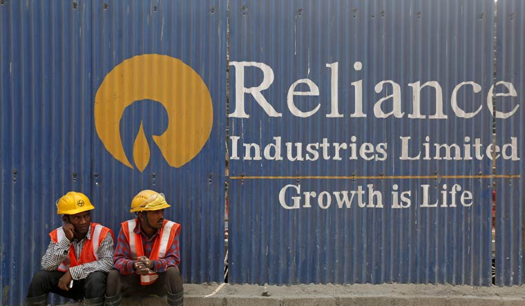 Labourers rest in front of an advertisement of Reliance Industries Limited at a construction site in Mumbai, India, March 2, 2016 | REUTERS/Shailesh Andrade/File Photo
