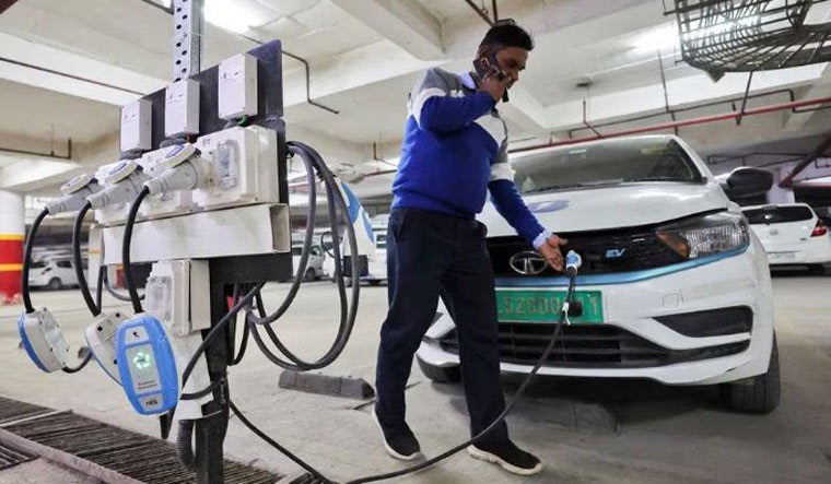 A man charges an electric vehicle (EV) at the charging hub in Gurugram | Reuters