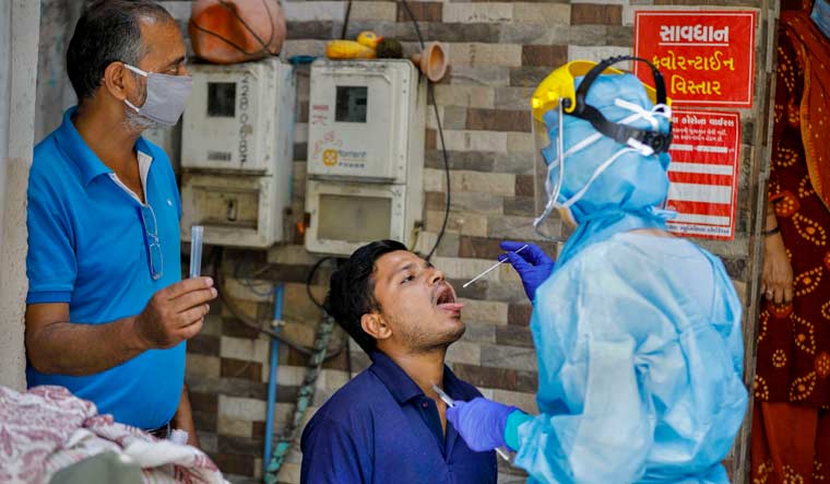 A lab technician wearing protective suit collects swab from a man for COVID-19 test in Ahmadabad | PTI