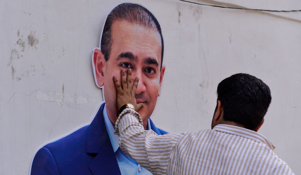 (File) A man puts his hand on the face of a cut-out of billionaire jeweller Nirav Modi during a protest in New Delhi | AFP
