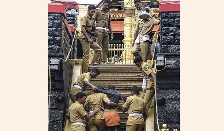 Policemen helps the devotees to climb up the 18 sacred steps for offering prayers at the Lord Ayyappa shrine, in Sabarimala | PTI