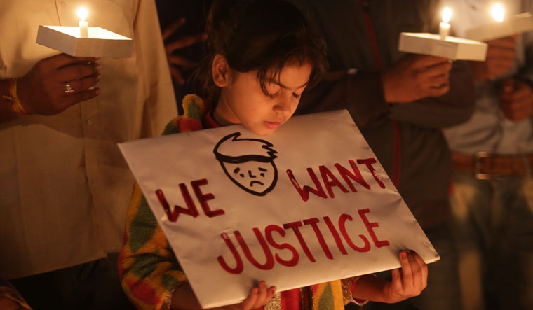 A third generation gas victim holds a placard during a candlelight vigil held by various gas victim organisations to commemorate Bhopal gas disaster in Bhopal on December 1 | AFP