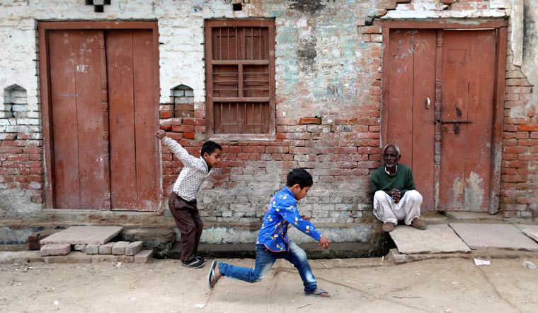 Children play as a man sits outside a house in Nayabans village in Bulandshahr district, Uttar Pradesh on December 5 | Reuters