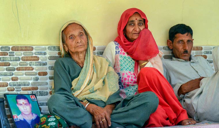 Family members grieve by a portrait of Aman, one of the 39 Indian workers feared killed in Iraq, at Passu village near Dharamshala | PTI