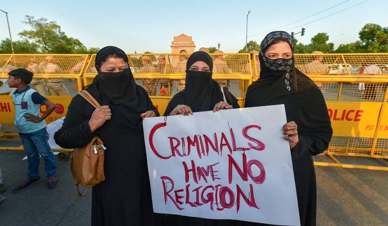 Burqa-clad women display a placard as they take part in a candlelight march at the India Gate in Delhi in protest over Kathua gang-rape case | PTI
