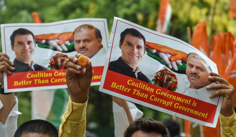 Congress supporters raise posters of party President Rahul Gandhi and JD(S) chief H.D. Kumarswamy after Karnataka Chief Minister B.S. Yeddyurappa announced his resignation | PTI