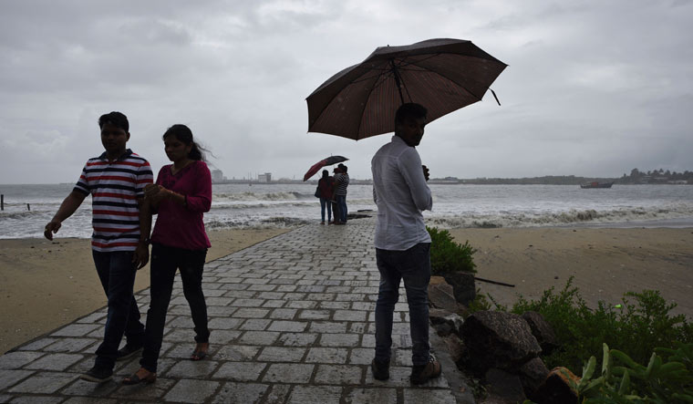 [File] People hold umbrellas during a drizzle as monsoon clouds hover over the Arabian Sea coast in Kochi | AP