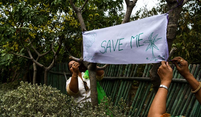 Women tie a banner on trees during the 'Save The Tree Campaign' in New Delhi | AFP