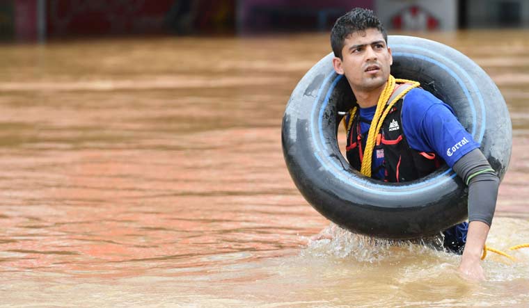 A Navy officer wades through water on a flooded road during rescue operation at Nedumbasseri near Kochi | Manorama