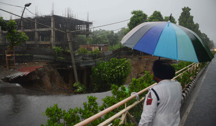 A  police personnel looks at a collapsed road due to heavy rain in Amritsar | AFP
