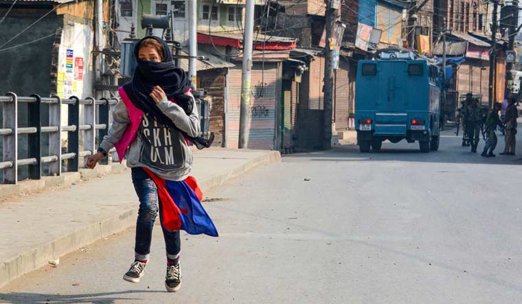 A girl runs for cover after throwing stones at security forces during a protest in Srinagar | PTI