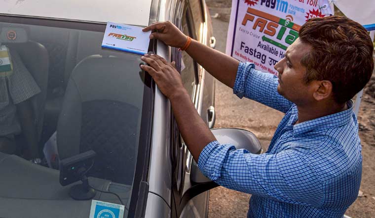 A worker fixes a FASTag sticker on the windscreen of a car, at Vashi Toll Plaza on Sion Panvel Highway, Mumbai, Friday, Nov. 29, 2019 | PTI