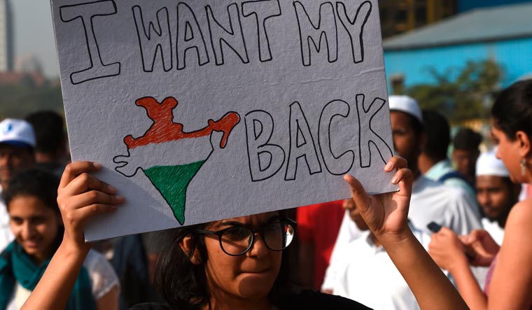 A protester holds a placard during a demonstration against  new citizenship law in Mumbai | AFP