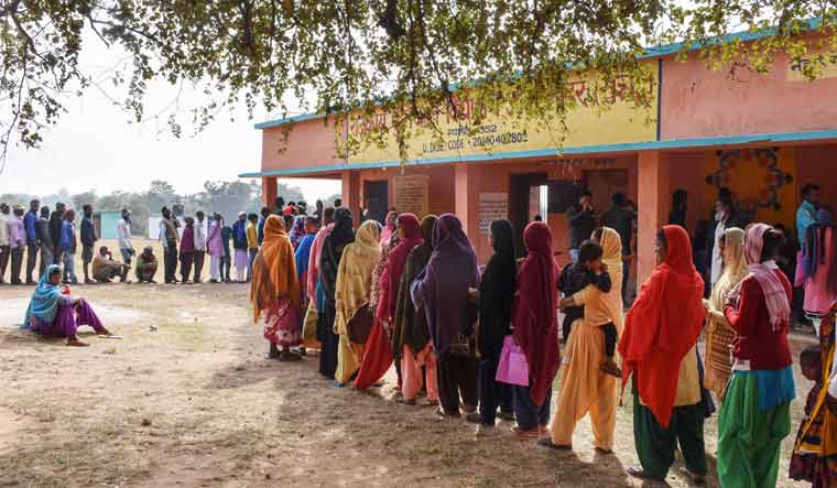 Voters stand in a queue at a polling station to cast their votes during the 2nd phase of Jharkhand Assembly Elections, in Khunti district | PTI