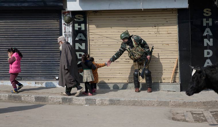 A paramilitary soldier shakes hand with a Kashmiri child as they walk past him during security lockdown in Srinagar | AP