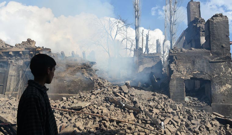 A young Kashmiri villager looks at the remains of a house destroyed during a deadly gun battle between militants and security forces in Tral area of Pulwama district | AFP