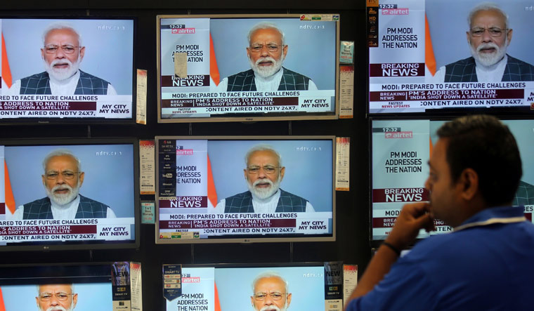 A man watches Prime Minister Narendra Modi addressing to the nation, on TV screens inside a showroom in Mumbai | Reuters