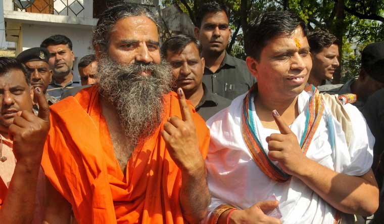 Yoga Guru Baba Ramdev and Acharya Balkrishna show their finger marked with indelible ink after casting vote during the first phase of general elections, at a polling station in Haridwar | PTI