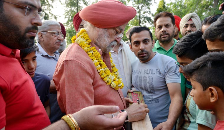 Union Minister and BJP candidate for Amritsar's parliament seat Hardeep Singh Puri signs autographs to his supporters during a morning walk at Ram Bagh Garden in Amritsar | AFP