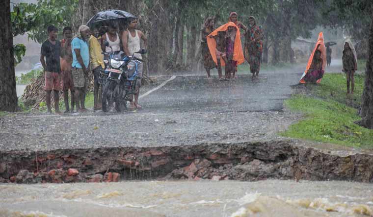People stand on a damaged embarkment washed out by the floods water due to heavy rainfalls in the hilly areas of neighbouring Nepal, at Forbesganj in Araria district of Bihar | PTI