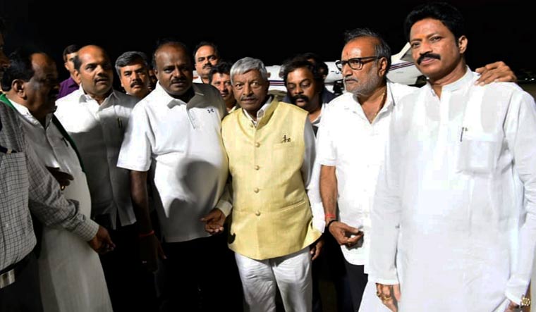 Karnataka Chief Minister H.D. Kumaraswamy talks with party MLAs and ministers at the HAL airport in Bengaluru after his 10 day personal trip to the US | PTI