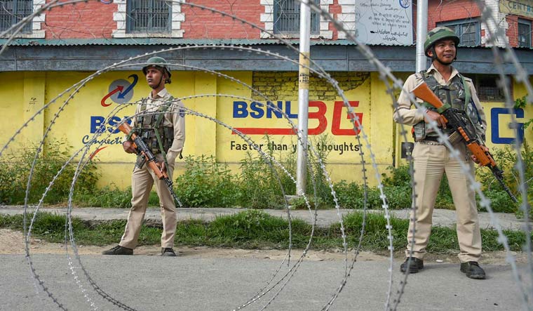 Security personnel stand guard near a blocked road during restrictions  in Srinagar | PTI