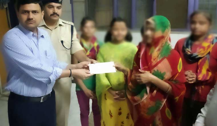 A UP government official hands over a cheque of Rs 25 lakh rupees to the family members of Unnao rape survivor, in Lucknow | PTI