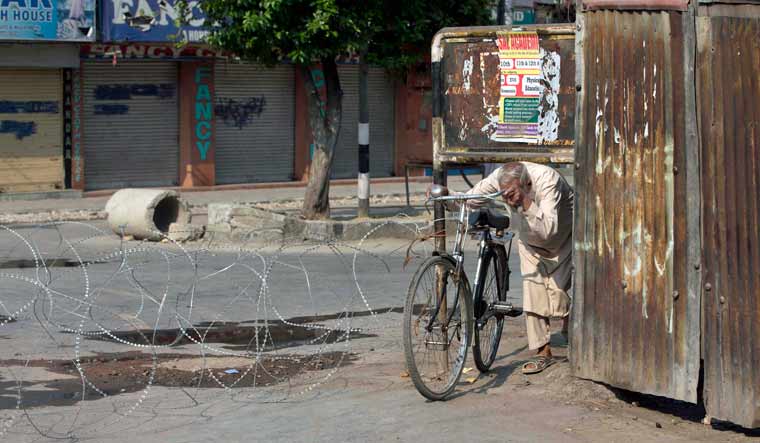 Kashmiri man crosses a barbwire checkpoint during lockdown in Srinagar, Indian controlled Kashmir | AP
