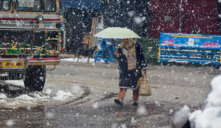 A Kashmiri woman walk as snow falls in Srinagar | AP