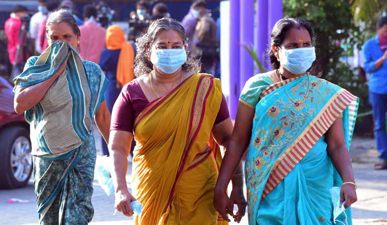 Residents and hospital visitors wearing face masks walk outside the Government Medical College in Thrissur, Kerala | AFP