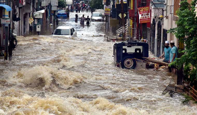 Floodwater gushes through a street following heavy rains, at Falaknuma, in Hyderabad | PTI