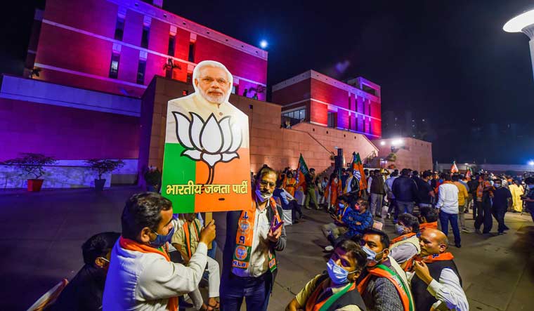 BJP workers hold a placard with Prime Minister Narendra Modi's picture to celebrate their party's lead in the Bihar Assembly polls, at BJP HQ in New Delhi | PTI